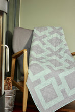 Load image into Gallery viewer, Shinersview Connected squares quilt laying over a chair in front of a wood burning stove